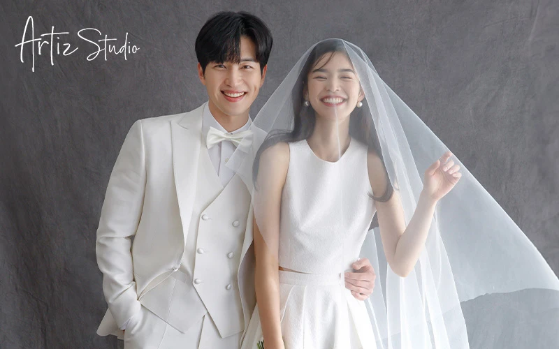 Newlyweds dressed in white wedding outfit, smiling widely